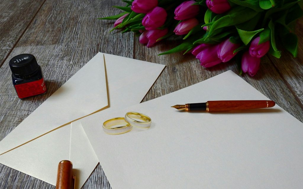 wedding rings on invitation with tulips and pen